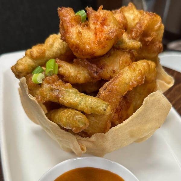 Crispy fried shrimp and green beans in a wonton wrapper bowl, garnished with scallions, with dipping sauce.