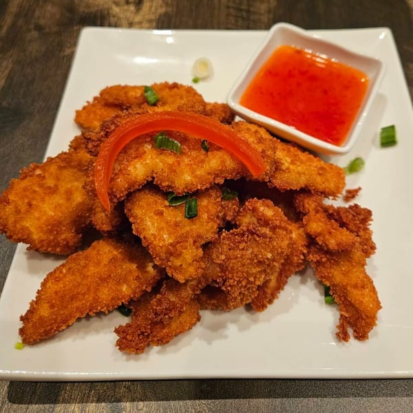 Crispy fried chicken pieces with red bell pepper, green onions, and a side of sweet chili sauce.