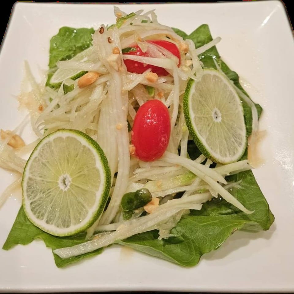 Erawan's Thai papaya salad with shredded papaya, cherry tomatoes, peanuts, and lime slices.
