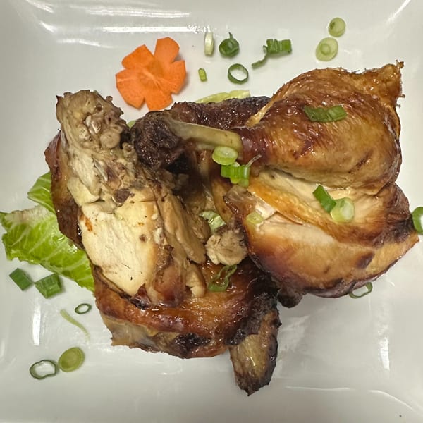 Erawan's roasted chicken, garnished with green onions, lettuce, and a carved carrot flower.