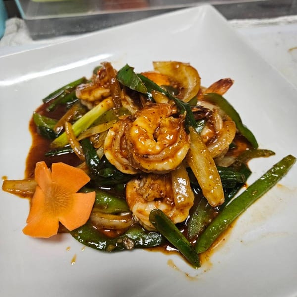 Erawan's spicy Thai shrimp stir-fry with green beans, onions, and a carrot garnish on a white plate.