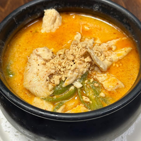 Erawan's Thai red curry with chicken, green beans, and crushed peanuts in a black bowl.