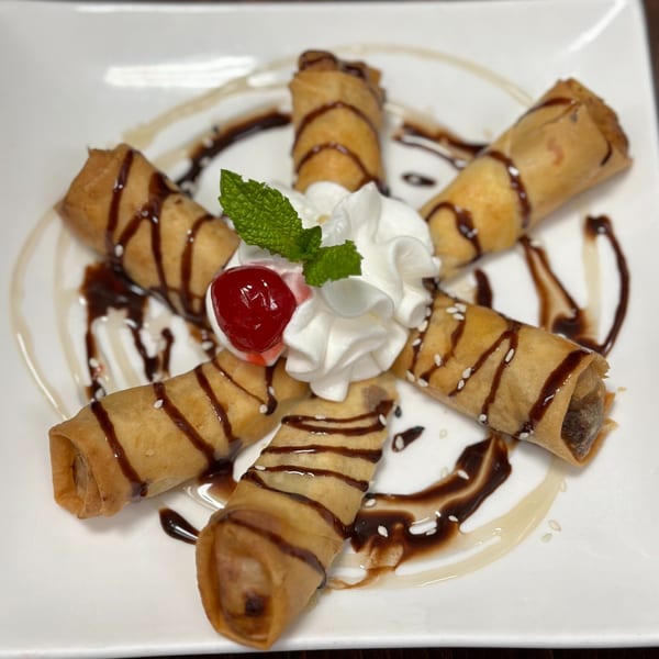 Erawan's fried banana spring rolls with chocolate drizzle, whipped cream, a cherry, and mint.