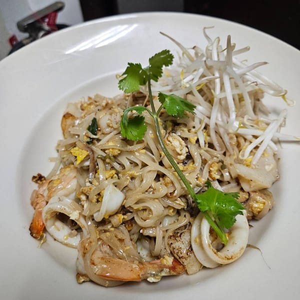 Erawan's Pad See Ew with shrimp, squid, egg, and bean sprouts, garnished with cilantro.