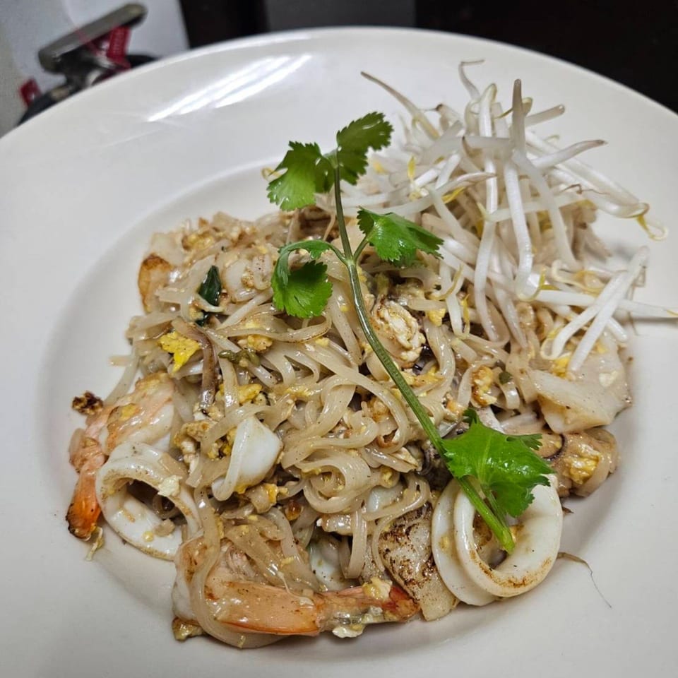 Erawan's Pad See Ew with shrimp, squid, egg, and bean sprouts, garnished with cilantro.