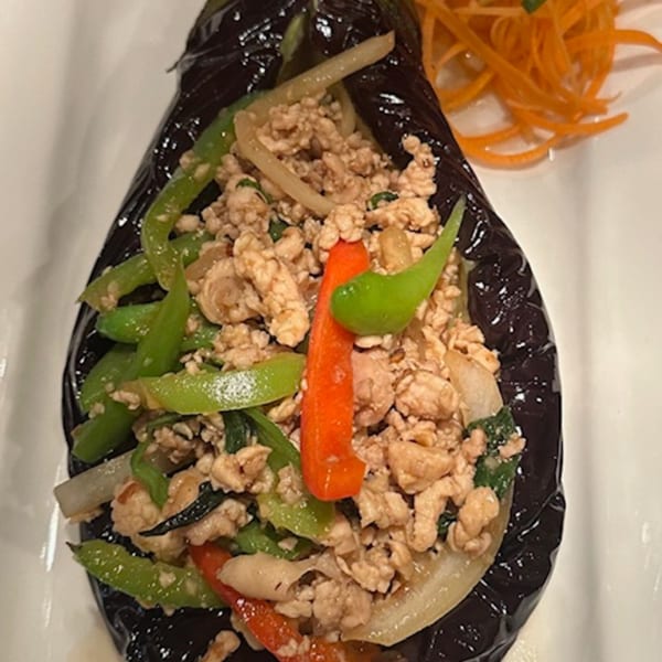 Thai eggplant dish with ground chicken, green beans, and red peppers, garnished with shredded carrots.