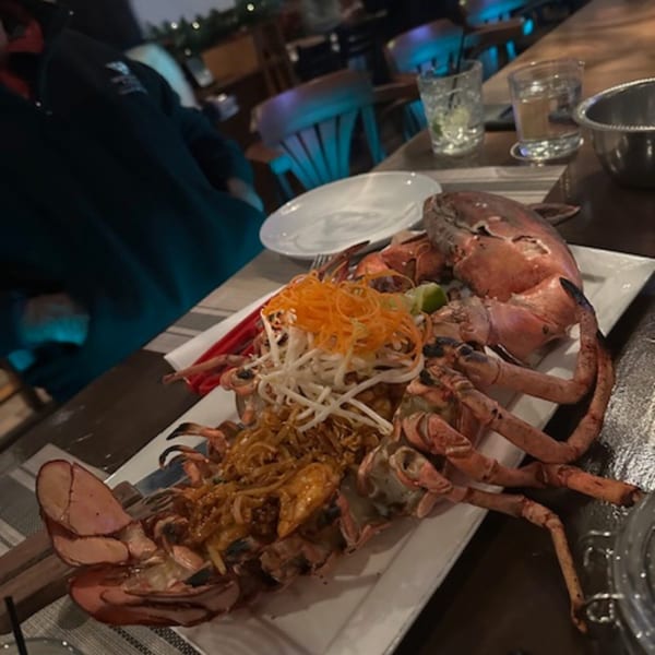 Whole grilled lobster, garnished with shredded carrots and bean sprouts, on a white platter at Erawan.
