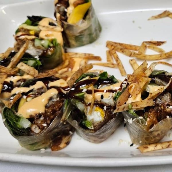 Erawan's fresh spring rolls with dark sauce, creamy dressing, sesame seeds, and crispy toppings.