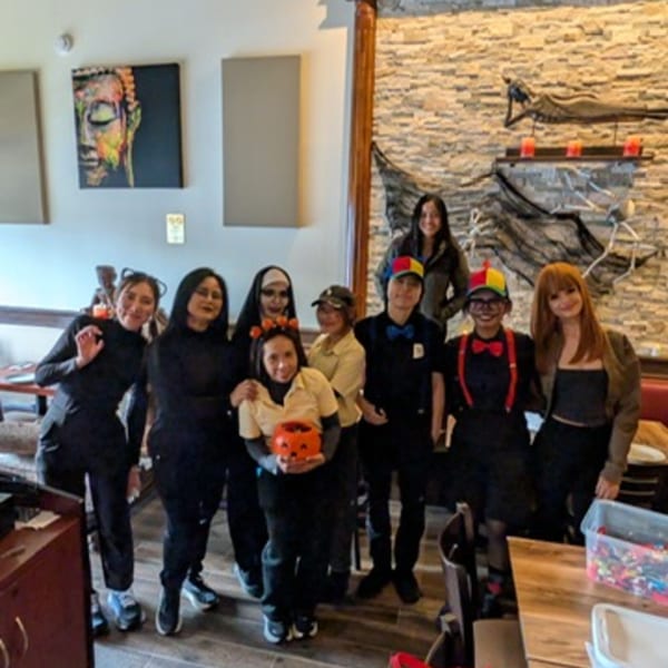 Erawan Thai restaurant staff in Halloween costumes pose together in the dining area.
