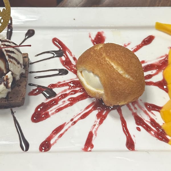 Erawan's fried ice cream dessert with raspberry and chocolate drizzle, alongside a brownie and mango slices.