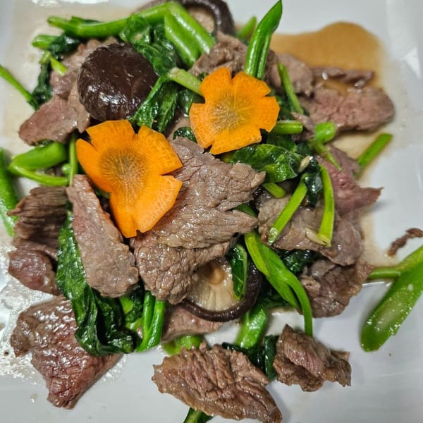 Erawan's Thai beef stir-fry with green vegetables, mushrooms, and carved carrot flowers.