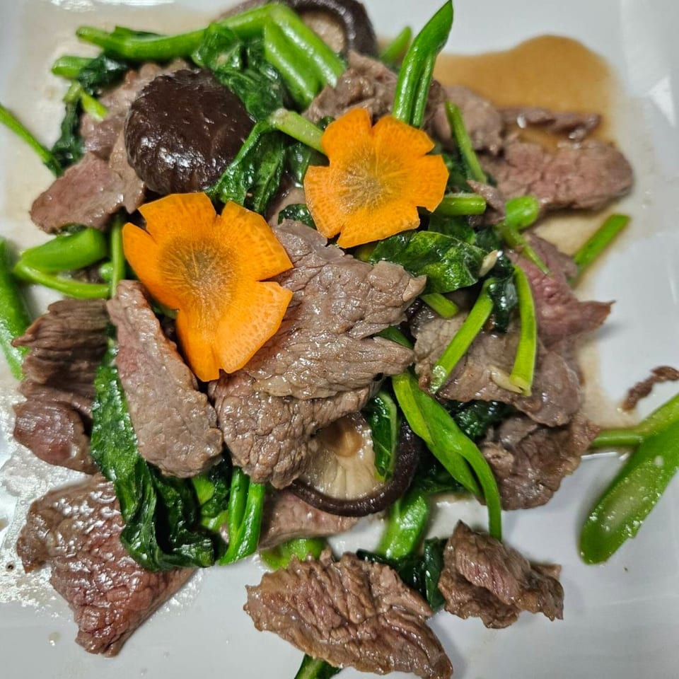 Erawan's Thai beef stir-fry with green vegetables, mushrooms, and carved carrot flowers.